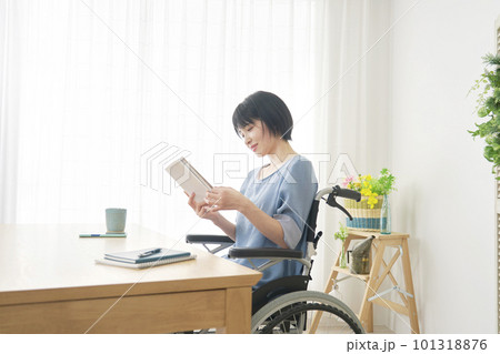リビングで読書する車椅子に乗った女性 101318876