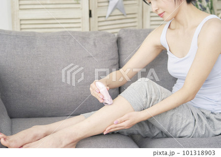 リビングで家庭用脱毛器で脚のセルフ脱毛をする女性 リビングで家庭用脱毛器で脚のセルフ脱毛をする女性 101318903