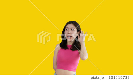 Asian woman eavesdropping or overhearing secret conversation isolated on yellow background, Gossip, Listening, Yellow background studio portrait. Asian woman eavesdropping or overhearing secret conversation isolated on yellow background, Gossip, Listening, Yellow background studio portrait. 101319735