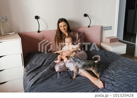 Mother with her baby song playing in the bed, playing with their dogs Mother with her baby song playing in the bed, playing with their dogs 101320428