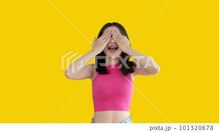 Young woman covering her face and eyes with her hands isolated, Cover your eyes with your hands for fear or prying eyes, Sneak peek, Yellow background. 101320678