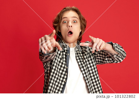 Excited young boy, student wearing checkered shirt pointing with finger and shocked facial expression over red studio background Excited young boy, student wearing checkered shirt pointing with finger and shocked facial expression over red studio background 101322802