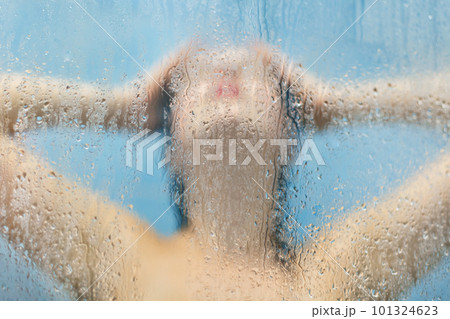People and care concept. Silhoette of beautiful nude woman poses in shower cabine, takes douche, takes care of her skin, poses aginst dewy sweat glass with drops. Washing and wellness concept People and care concept. Silhoette of beautiful nude woman poses in shower cabine, takes douche, takes care of her skin, poses aginst dewy sweat glass with drops. Washing and wellness concept 101324623