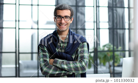 Shot of a handsome young businessman standing alone in his office with his arms folded. Shot of a handsome young businessman standing alone in his office with his arms folded. 101330032