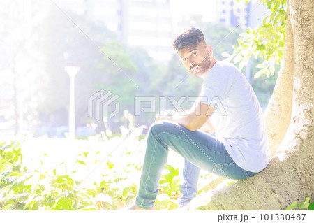 木漏れ日公園の木の下に座るインド人男性 101330487