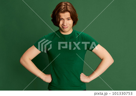 Young handsome boy, guy standing with hands on waist with confident facial expression over green studio background. Superman, can do everything Young handsome boy, guy standing with hands on waist with confident facial expression over green studio background. Superman, can do everything 101330753