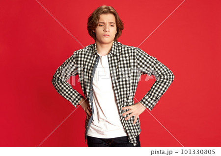 Young man, guy wearing white t-shirt standing with dislike face and hands on belt over red background. Unpleasant emotions 101330805