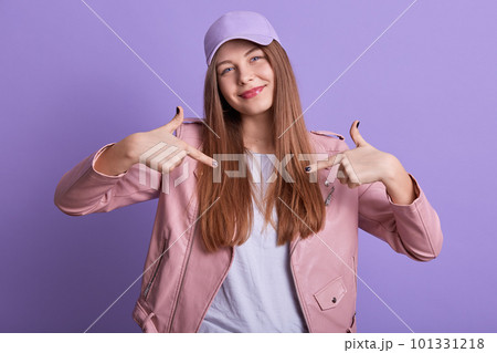 Indoor image of beautiful delighted sweet young girl raising hands, making gesture, showing direction with forefingers, having peaceful facial expression, being in good mood. Emotions concept. Indoor image of beautiful delighted sweet young girl raising hands, making gesture, showing direction with forefingers, having peaceful facial expression, being in good mood. Emotions concept. 101331218