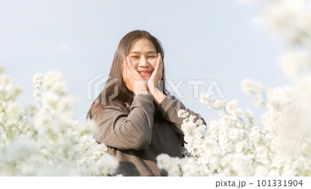 Asian woman stands among a white margaret flower. 101331904