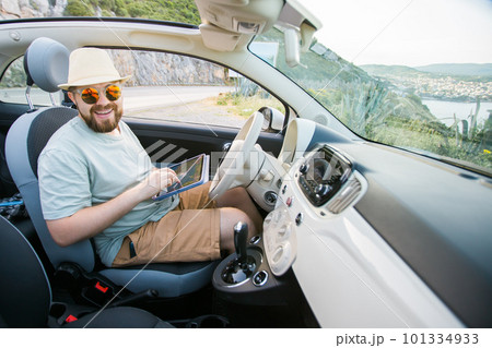 Hipster man looking on location navigation map in car, tourist traveler driving and hold in male hands europe cartography, view and plan tourist way road, trip in transportation cabriolet auto 101334933