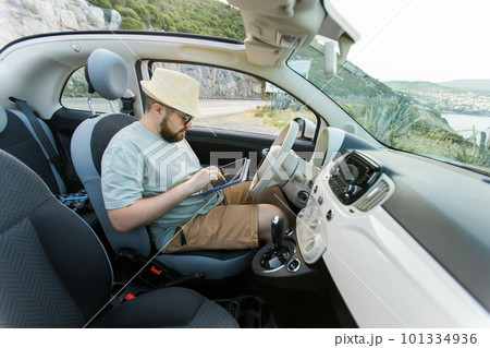 Hipster man looking on location navigation map in car, tourist traveler driving and hold in male hands europe cartography, view and plan tourist way road, trip in transportation cabriolet auto Hipster man looking on location navigation map in car, tourist traveler driving and hold in male hands europe cartography, view and plan tourist way road, trip in transportation cabriolet auto 101334936