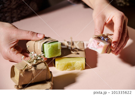 Close-up woman's hand holding bars of homemade cold-pressed soap with essential oils and natural herbal ingredients. Beauty treatment. Skin, hair and body care concept. Organic cosmetic eco products Close-up woman's hand holding bars of homemade cold-pressed soap with essential oils and natural herbal ingredients. Beauty treatment. Skin, hair and body care concept. Organic cosmetic eco products 101335622