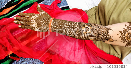 Beautiful artwork drawn on the hand of an Indian bride with herbal heena in wet condition. 101336834