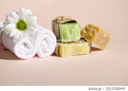 Spa set with two rolled white towels, chamomile flower and stack of organic natural soap bars with natural ingredients on isolated beige background. Horizontal shot. Still life. Copy advertising space Spa set with two rolled white towels, chamomile flower and stack of organic natural soap bars with natural ingredients on isolated beige background. Horizontal shot. Still life. Copy advertising space 101338044