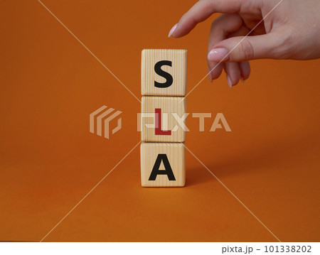 SLA - Service Level Agreement. Wooden cubes with word SLA. Businessman hand. Beautiful orange background. Business and Service Level Agreement concept. Copy space. 101338202