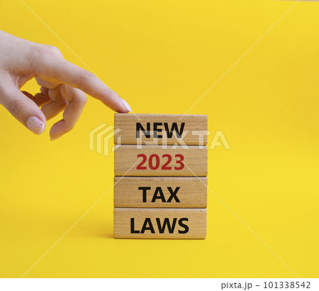 New 2023 Tax Law symbol. Wooden blocks with words New 2023 Tax Law. Beautiful yellow background. Businessman hand. Business and New 2023 Tax Law concept. Copy space. 101338542