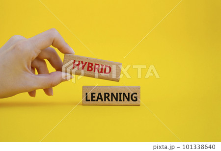 Hybrid learning symbol. Concept word Hybrid learning on wooden blocks. Businessman hand. Beautiful yellow background. Business and Hybrid learning concept. Copy space Hybrid learning symbol. Concept word Hybrid learning on wooden blocks. Businessman hand. Beautiful yellow background. Business and Hybrid learning concept. Copy space 101338640