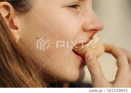 Close up of young girl's face eating waffle cup, side view Close up of young girl's face eating waffle cup, side view 101339643