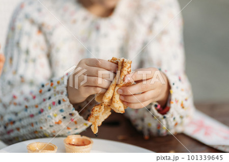 Child's hands holding pancake crepe over plate with toppings 101339645