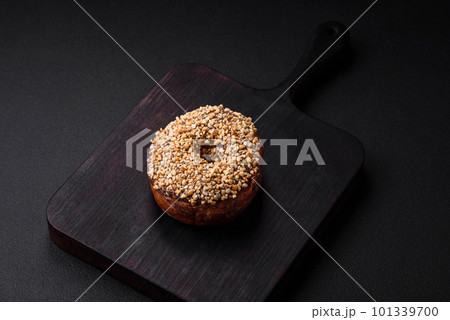 Delicious donut with cream filling and nuts on a dark concrete background 101339700
