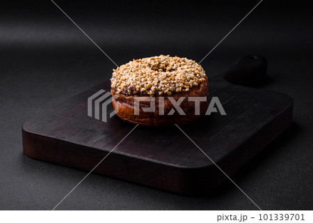 Delicious donut with cream filling and nuts on a dark concrete background 101339701