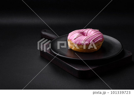 Delicious donut with cream filling and nuts on a dark concrete background 101339723