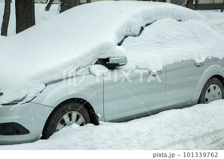 gray car covered with a snowdrift blocked in the parking lot, snowy spring morning cataclysm. gray car covered with a snowdrift blocked in the parking lot, snowy spring morning cataclysm. 101339762