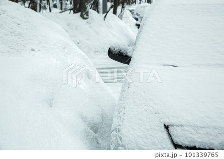 huge drifts of snow on the street with parked snow-covered cars, a featureless vehicle frostbitten by winter weather. 101339765
