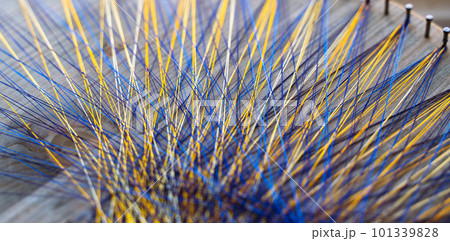 Colored thread mandala on a wooden board with nails. Mandala Moon Harmony Sun esotericism and psychology pictures from yellow and blue silk threads. 101339828