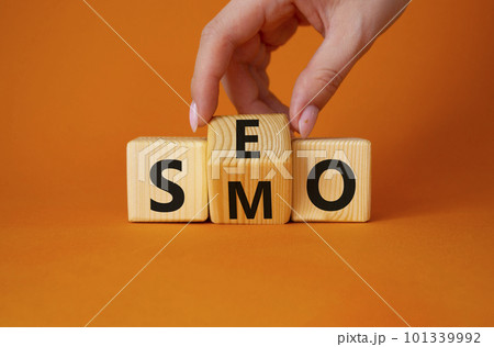 SEO vs SMO symbol. Businessman hand turns wooden cubes and changes the word SMO to SEO. Beautiful orange background. SEO vs SMO and business concept. Copy space 101339992