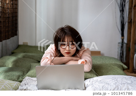 寝転んでノートパソコンを使う若い女性 寝転んでノートパソコンを使う若い女性 101345786