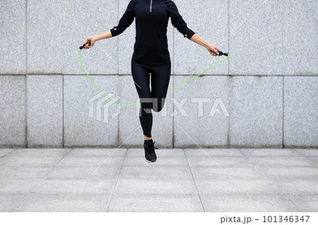 Fitness woman rope skipping against city wall Fitness woman rope skipping against city wall 101346347