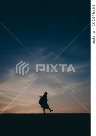 夕焼けに佇むシルエットの女性 101346561