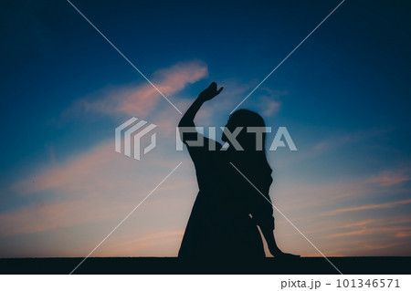 夕焼けに佇むシルエットの女性 101346571
