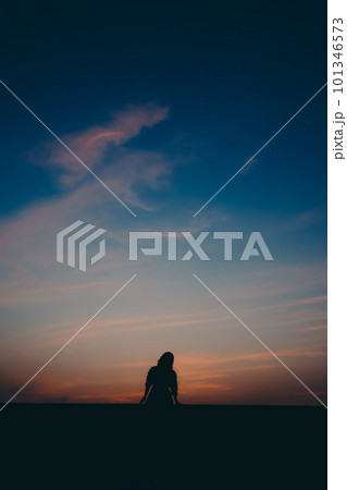 夕焼けに佇むシルエットの女性 101346573