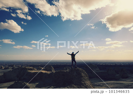 Successful female backpacker feel free on desert hill top 101346635