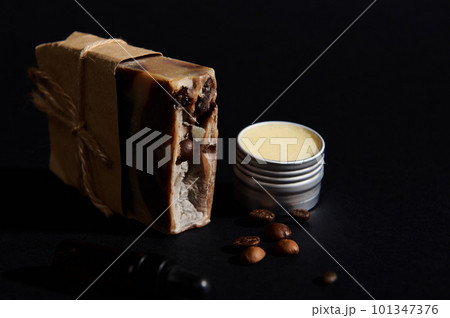 A bar with cold-pressed organic homemade soap with coffee beans and jar with wax, isolated black background. Natural ecological cosmetic products concept. Home spa, hygiene, skin and body care concept 101347376