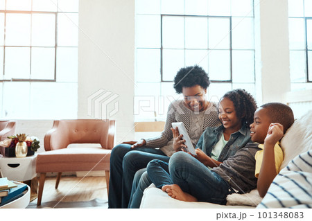 Family with tablet, watch and relax at family home together, spending quality time together with technology. Black people, mother and children on sofa with device, internet wifi and social media Family with tablet, watch and relax at family home together, spending quality time together with technology. Black people, mother and children on sofa with device, internet wifi and social media 101348083