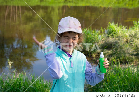 Girl sprays mosquito spray on the skin in nature that bite her hands and feet. Protection from insect bites, repellent safe for children. Outdoor recreation, against allergies. Summer time Girl sprays mosquito spray on the skin in nature that bite her hands and feet. Protection from insect bites, repellent safe for children. Outdoor recreation, against allergies. Summer time 101348435
