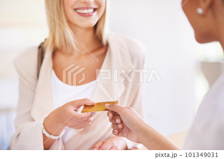 Can I use my debit card. A young woman handing over her credit card to a salesperson. Can I use my debit card. A young woman handing over her credit card to a salesperson. 101349031