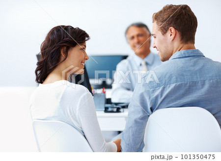 Couple discussing financial plan with advisor. Happy couple discussing financial plan in office with male advisor. 101350475