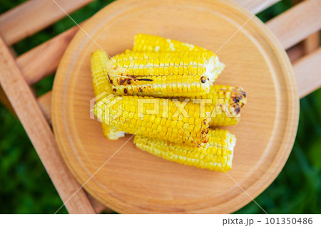 Delicious, sweet young grilled popcorn lies on a wooden board, outdoor recreation, proper nutrition. Delicious, sweet young grilled popcorn lies on a wooden board, outdoor recreation, proper nutrition. 101350486