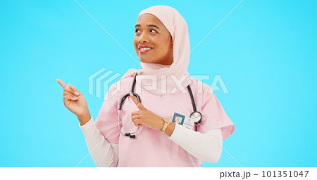 Woman doctor pointing to mockup isolated on blue background for healthcare presentation or product placement space. Happy face of nurse or medical muslim person show advertising mock up in studio Woman doctor pointing to mockup isolated on blue background for healthcare presentation or product placement space. Happy face of nurse or medical muslim person show advertising mock up in studio 101351047