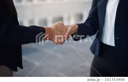 Deal with people who get thing a done. Cropped of two businesswomen shaking hands against a city background. 101353406