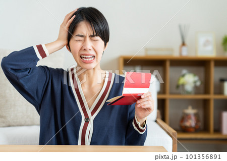 通帳を見て悩む若い女性 101356891