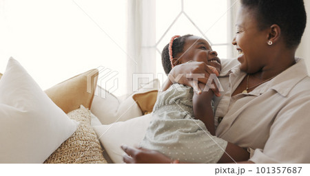 Happy family, mother and child play in a house with love, laughing and freedom on a sofa in a living room. Smile, girl and funny mama enjoy having fun, bonding and tickling quality time together 101357687