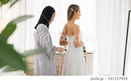 Happy bride in wedding dress, friends helping with knot on luxury corset back string and young women together in home. Asian woman supporting hug, marriage ready preparation and bridesmaid happiness 101357693