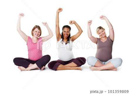 Pregnant, happy, and healthy, women sitting on the floor, arms raised in celebration of new life. Mothers, friends, and happiness during pregnancy, a group of future moms workout on white background Pregnant, happy, and healthy, women sitting on the floor, arms raised in celebration of new life. Mothers, friends, and happiness during pregnancy, a group of future moms workout on white background 101359809