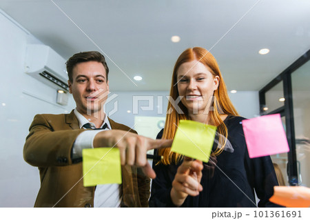 Business people holding pen and put sticky notes on glass wall in office. Business people holding pen and put sticky notes on glass wall in office. 101361691