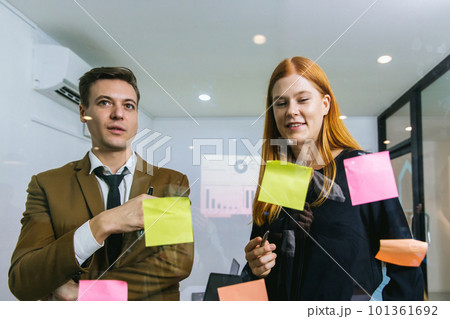 Business people holding pen and put sticky notes on glass wall in office. Business people holding pen and put sticky notes on glass wall in office. 101361692